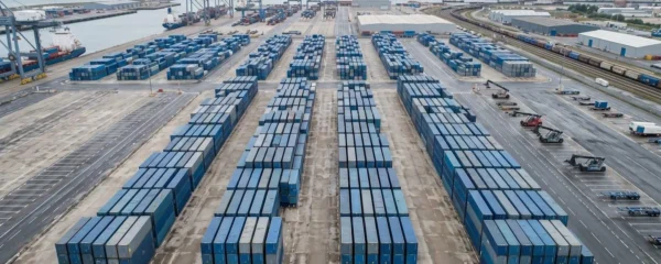 Vue aérienne d'une zone de stockage industriel avec plusieurs conteneurs maritimes rangés dans un dépôt professionnel