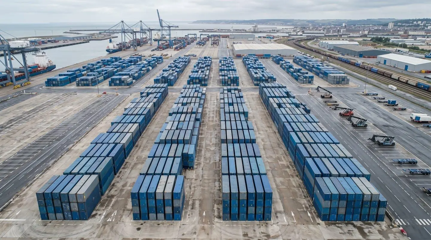 Vue aérienne d'une zone de stockage industriel avec plusieurs conteneurs maritimes rangés dans un dépôt professionnel